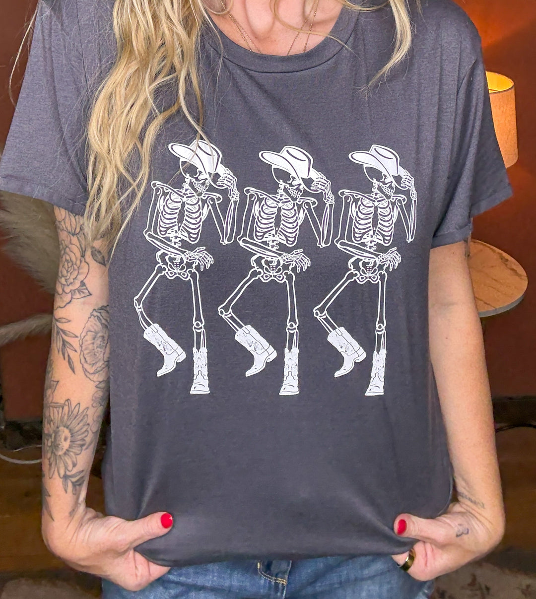 Person wearing a gray t-shirt with white skeleton cowboy graphics.