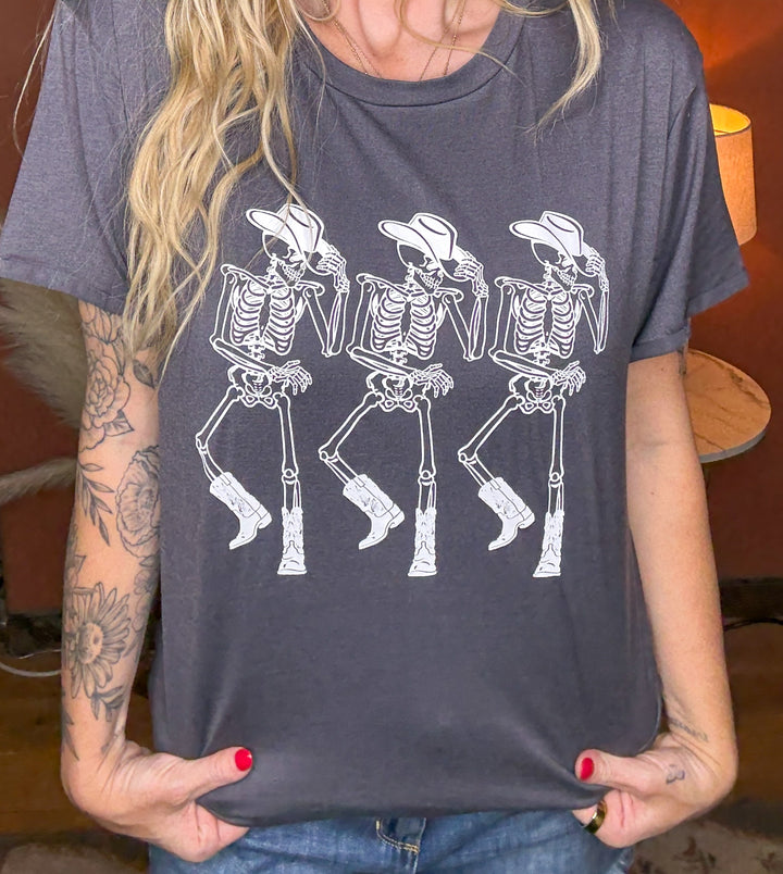 Person wearing a gray t-shirt with white skeleton cowboy graphics.