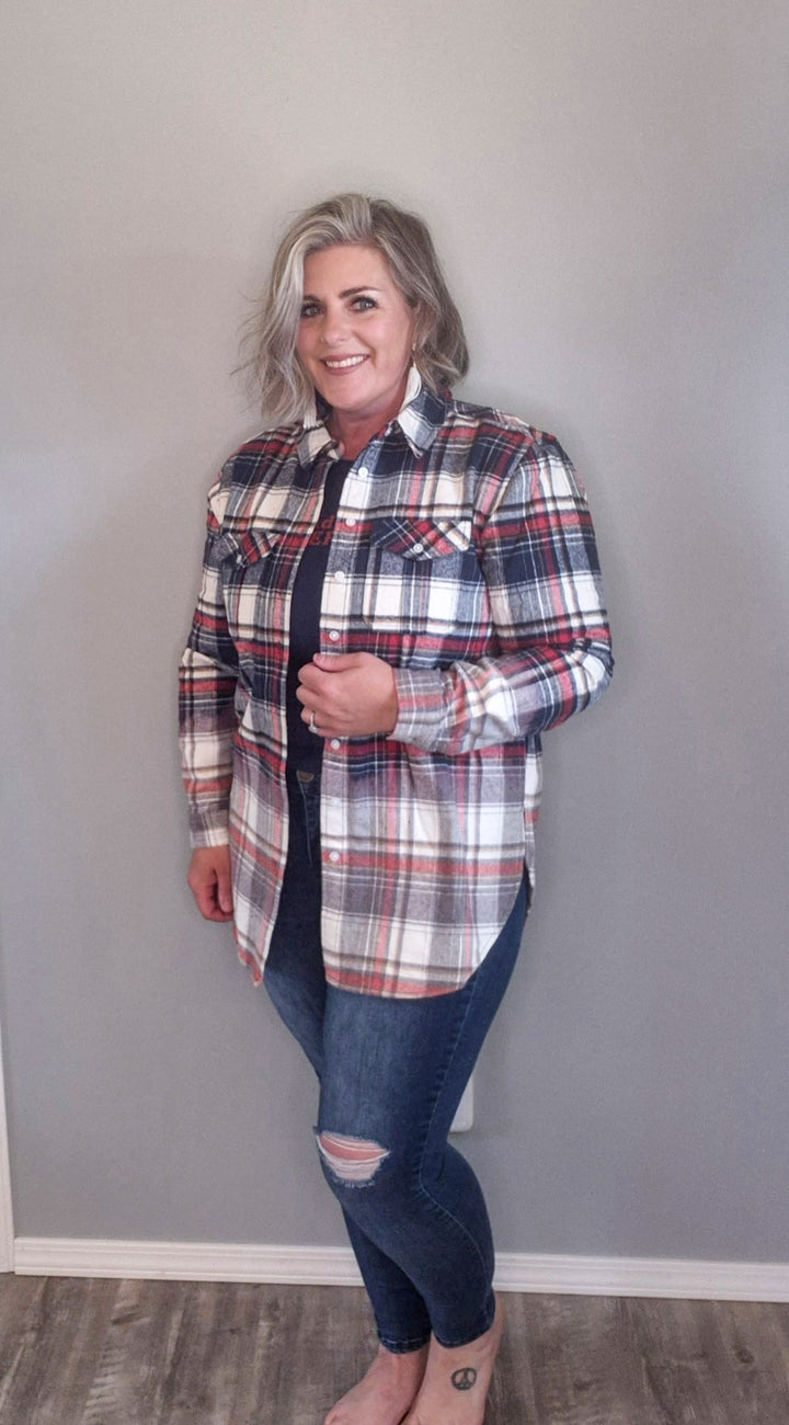 Woman wearing button up flannel that is red, white, and blue with a pair of denim skinny jeans