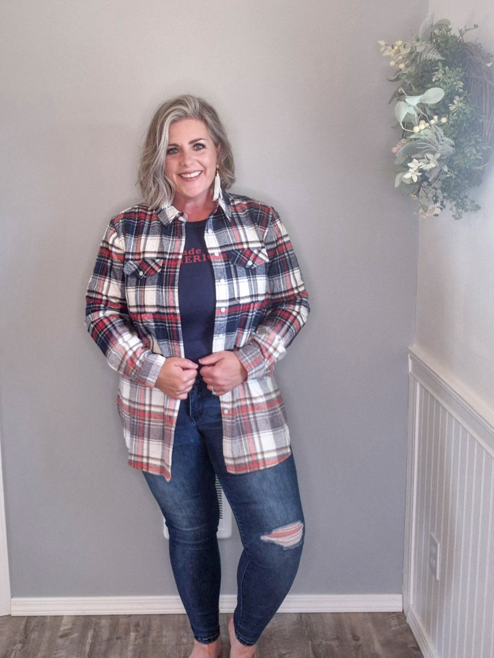 Woman wearing button up flannel that is red, white, and blue with a pair of denim skinny jeans