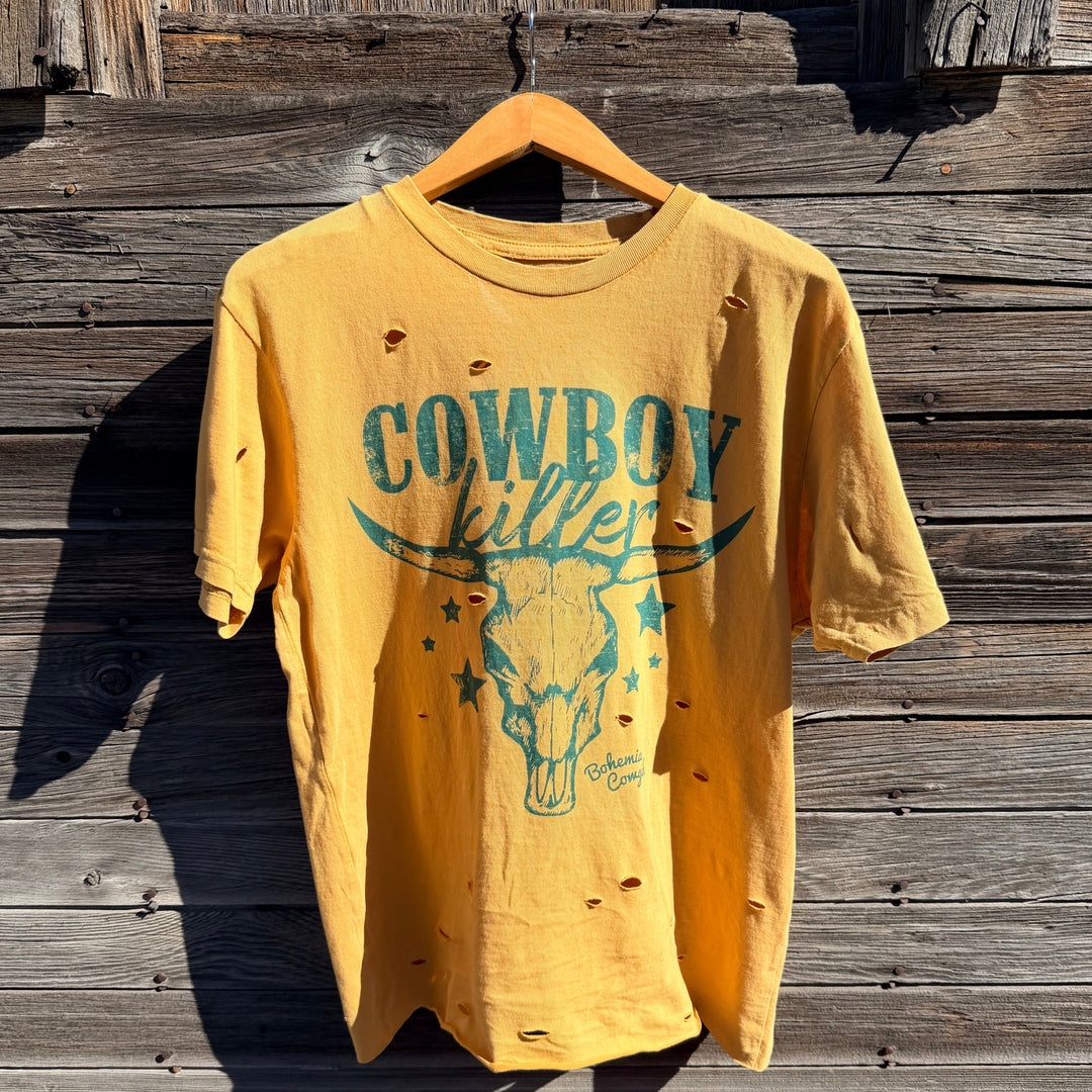 Yellow t-shirt with cowboy killer and graphic design on a wooden surface