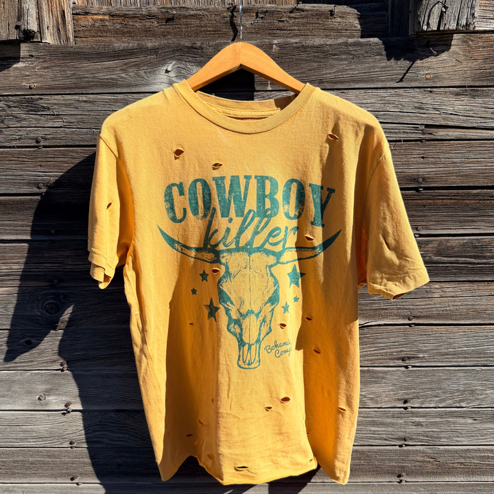 Yellow t-shirt with cowboy killer and graphic design on a wooden surface