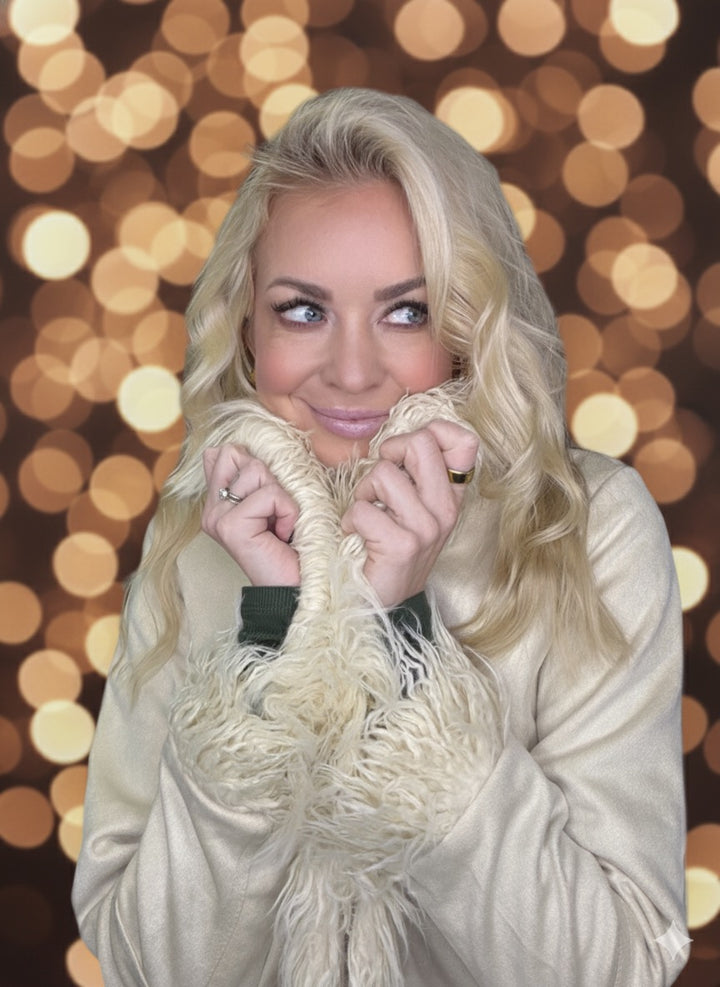 Woman wearing  a beige faux fur coat with a blurred bokeh background