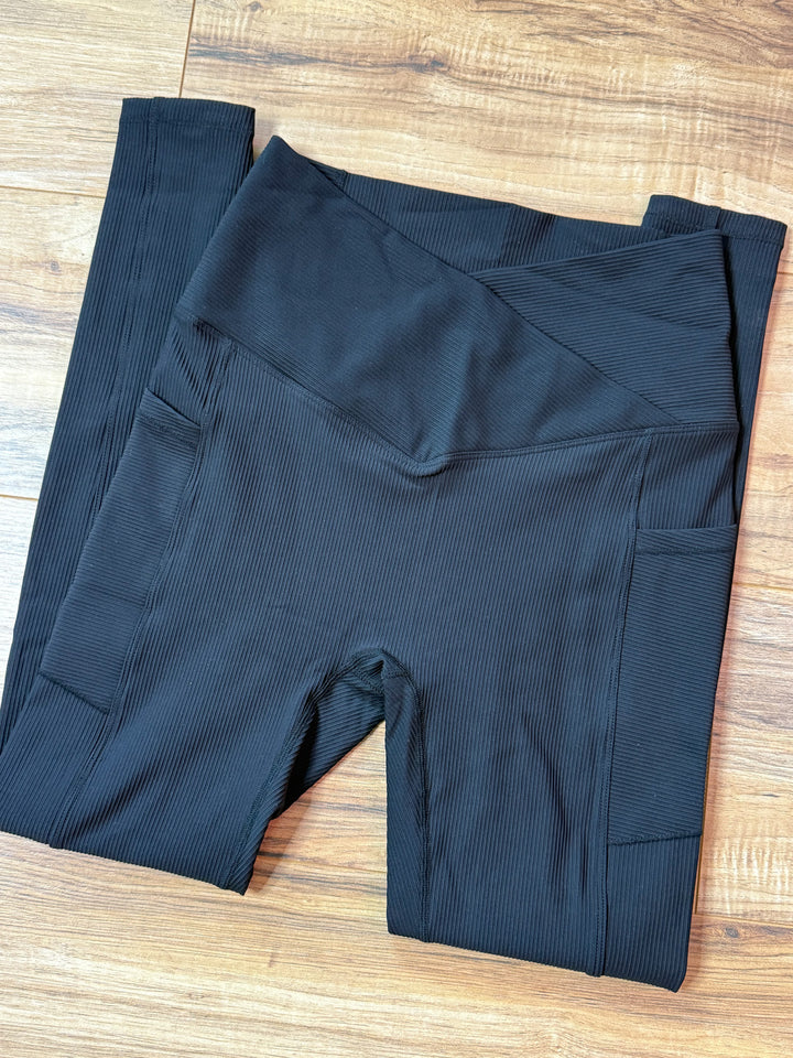 flat lay photo of black ribbed leggings showing detail of pockets and crossover waistband 