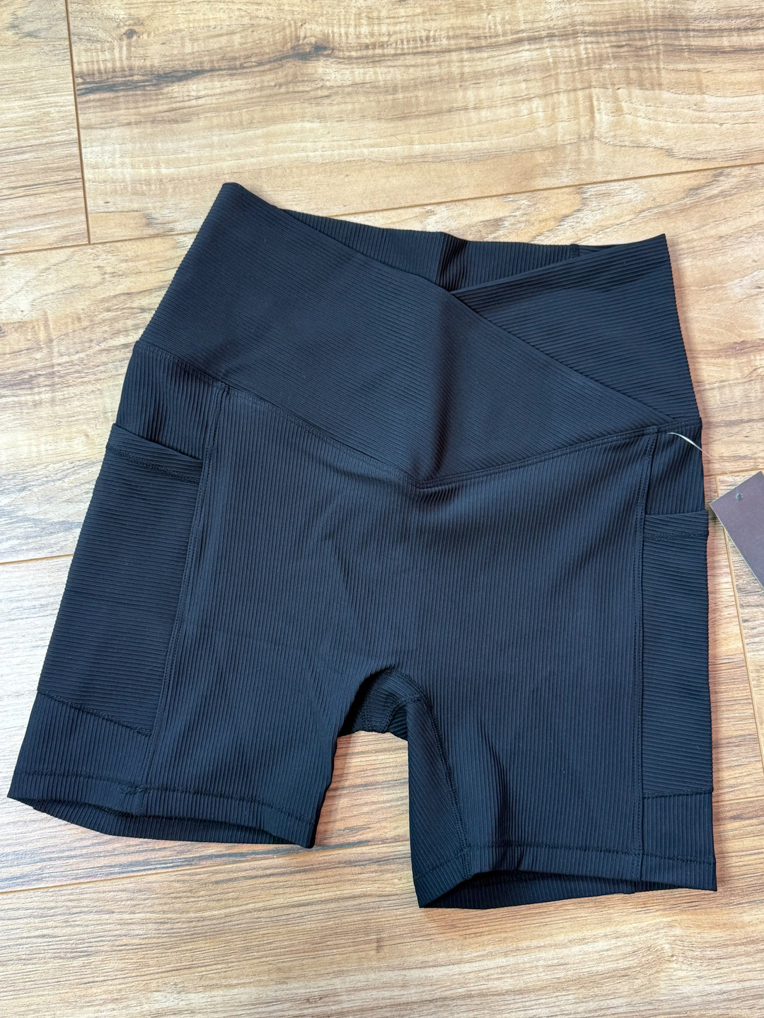 flat lay photo of black ribbed biker shorts showing detail of pockets and crossover waistband 