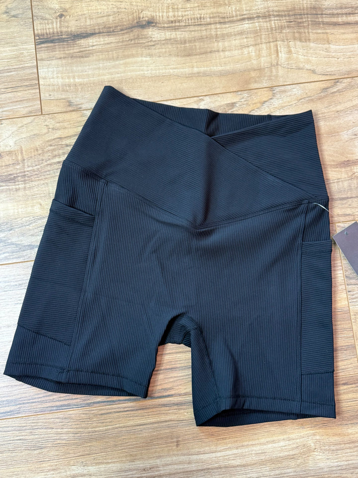 flat lay photo of black ribbed biker shorts showing detail of pockets and crossover waistband 