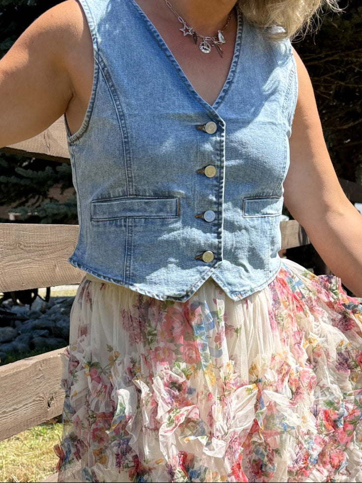 Model wearing a denim button up vest with v-neck. Functional buttons and sleeveless. 