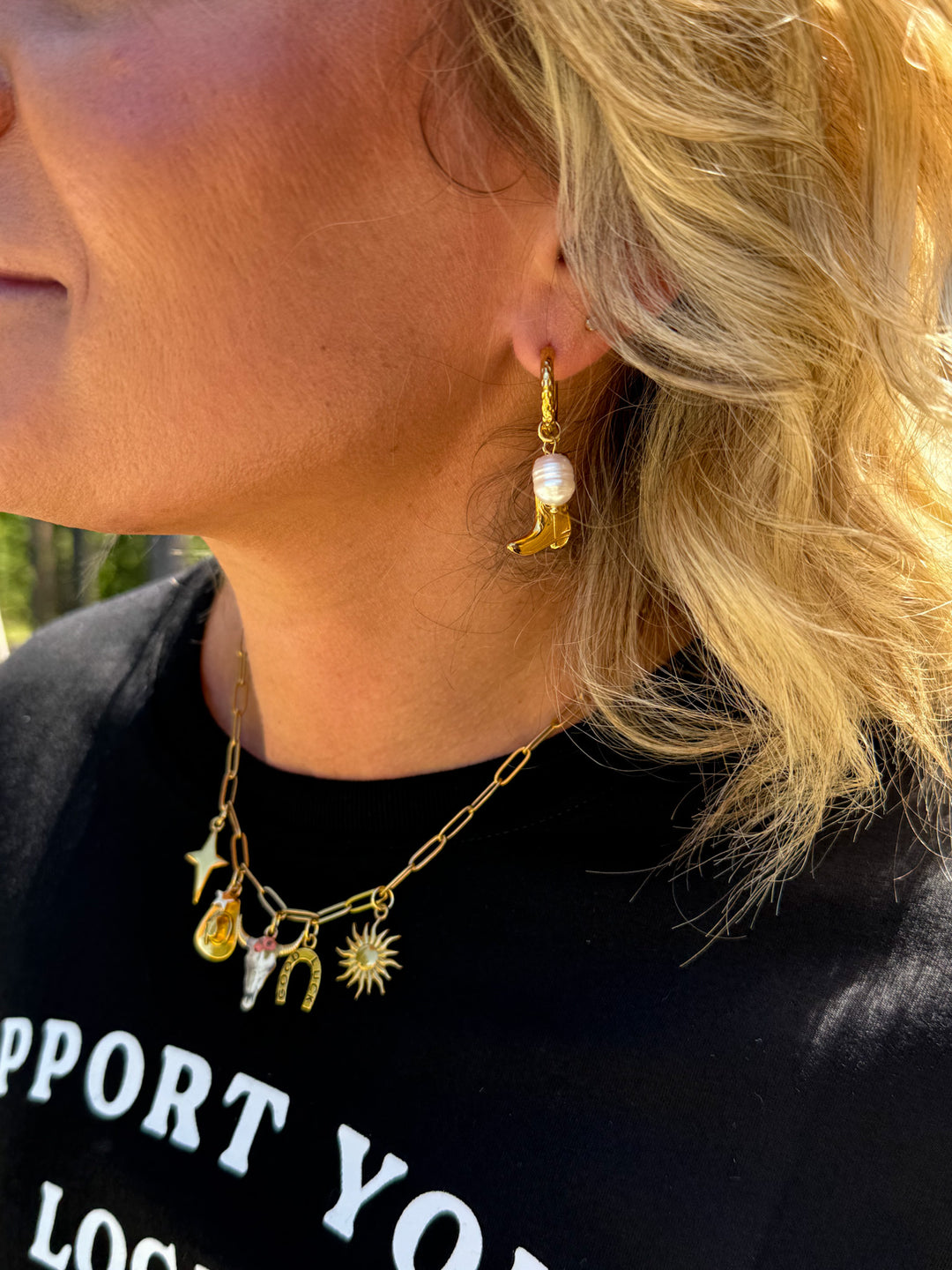 woman wearing gold huge earrings with a cowboy boot and pearl
