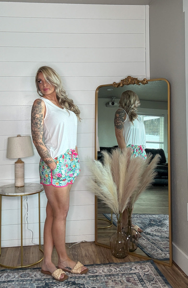 The Wild Blossom Shorts - mid-rise,  tie waist drawstring for adjustability, and side pockets for convenience,  relaxed fit. Flower pattern.