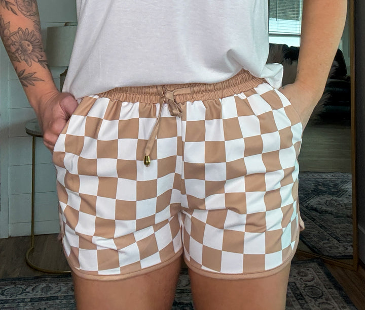 The Checkmate Shorts - mid-rise,  tie waist drawstring for adjustability, and side pockets for convenience,  relaxed fit. neutral checkered print