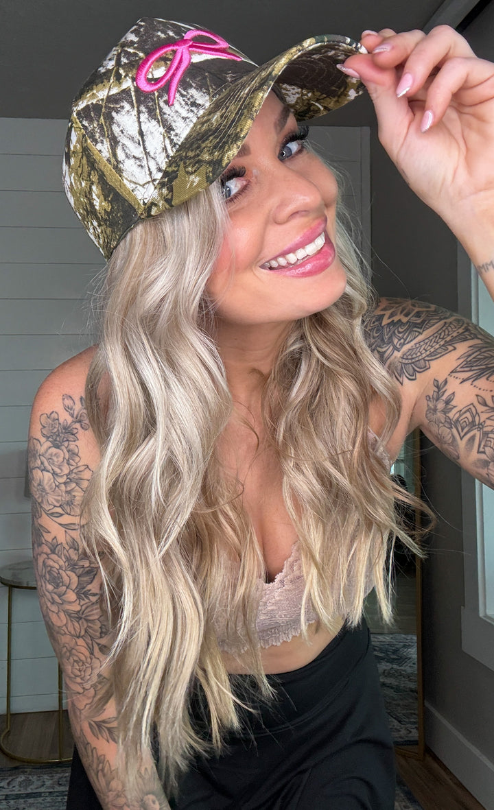 The Backroad Babe Hat - duck camo print, breathable mesh backing, and bold embroidery of a bow.