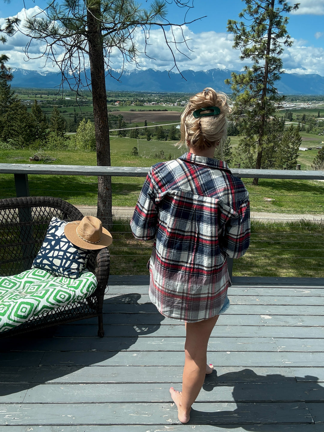 Woman wearing button up flannel that is red, white, and blue with a pair of denim shorts