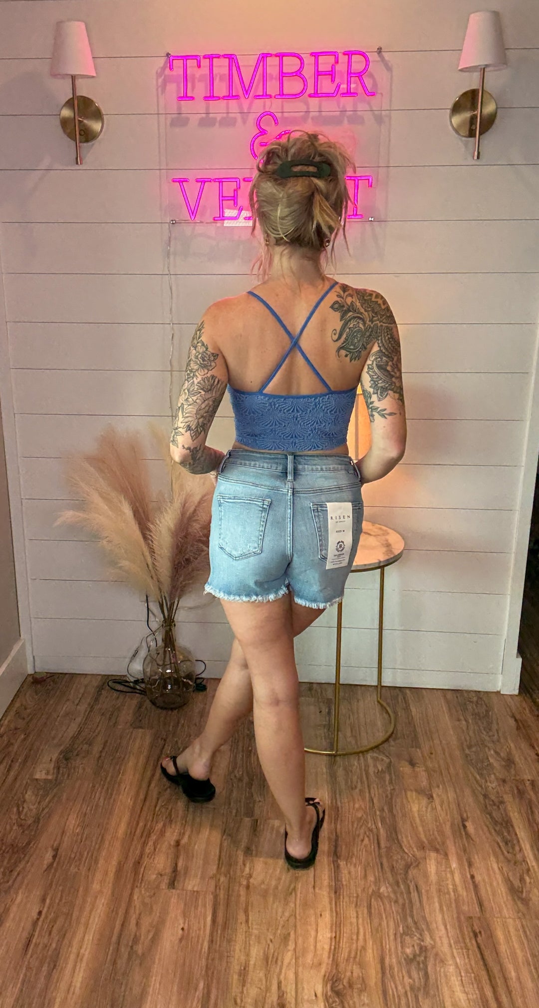 Women wearing blue tank showing the back criss cross design with denim shorts