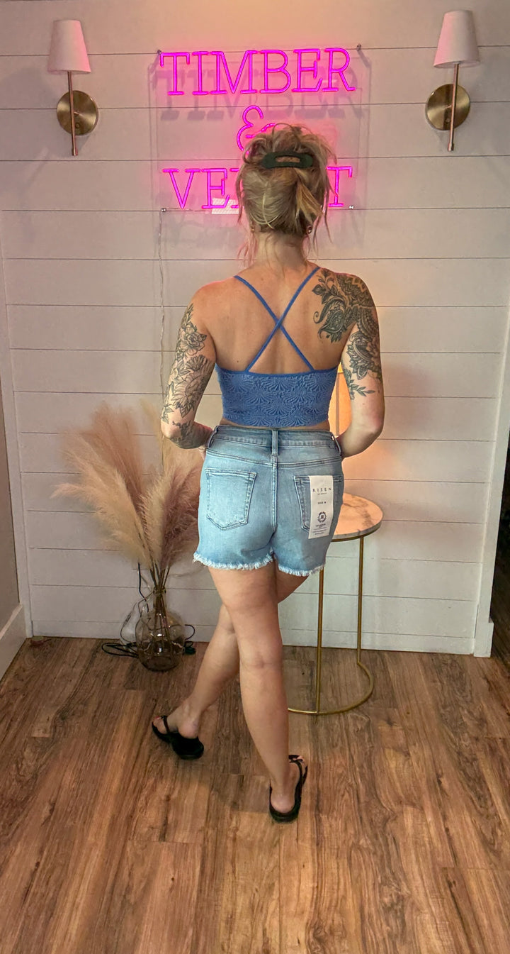 Women wearing blue tank showing the back criss cross design with denim shorts