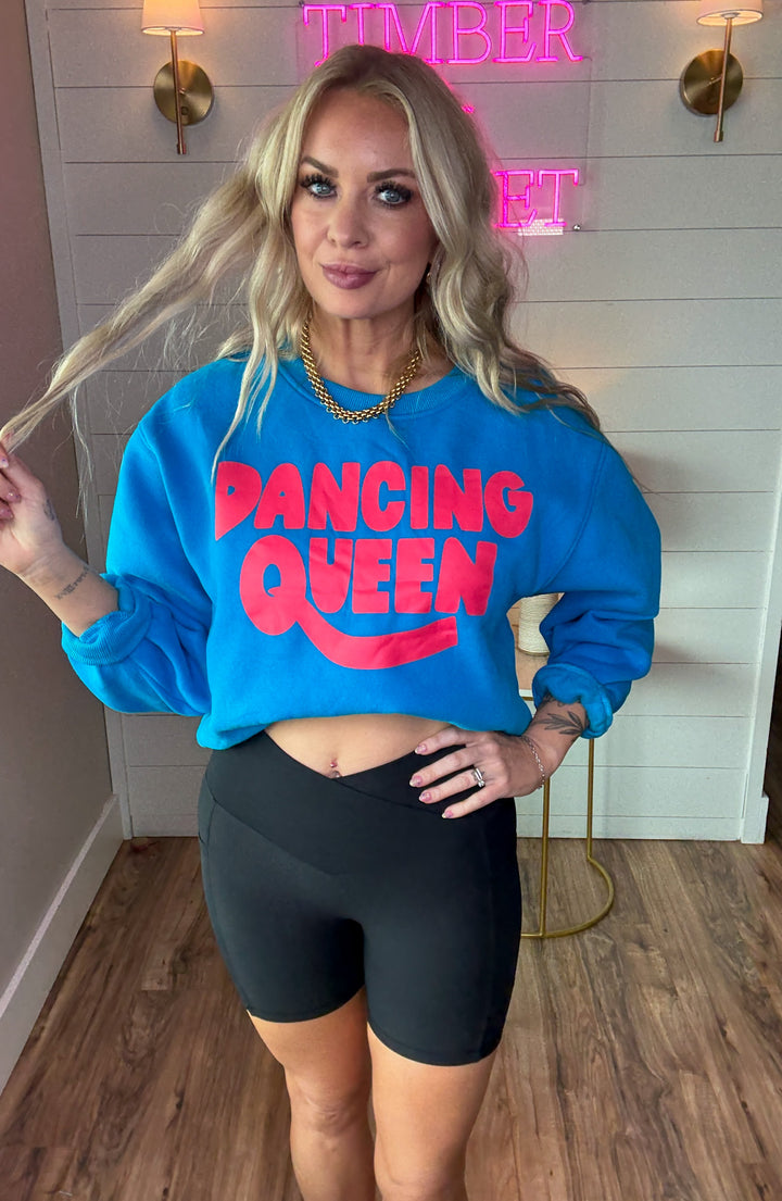 Woman wearing black ribbed biker shorts with side pockets and dancing queen crewneck sweatshirt in bold colors of blue and pink