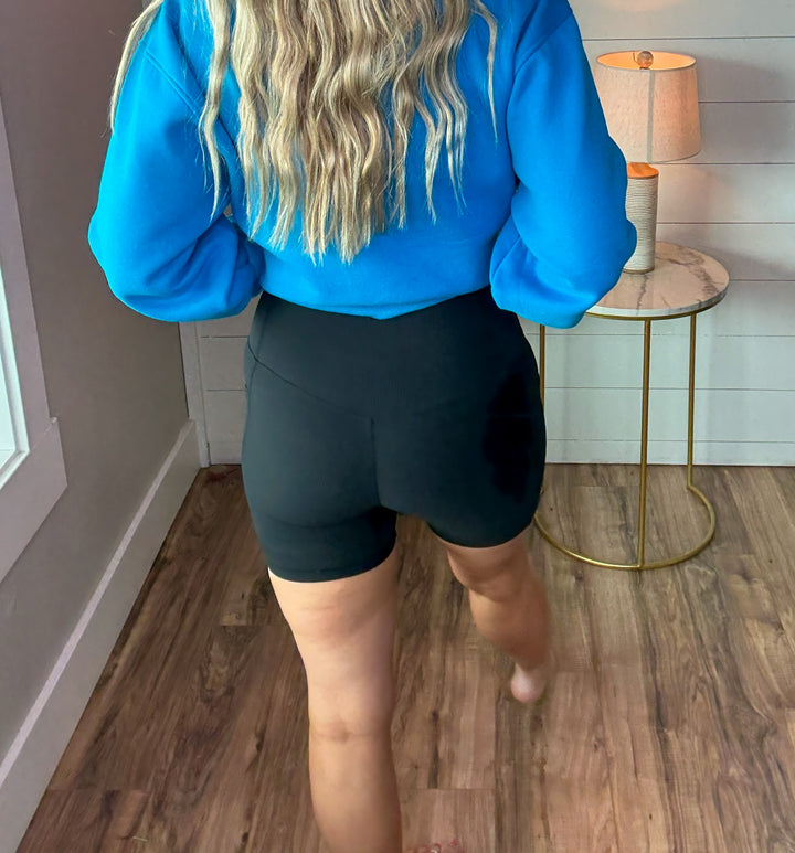 Woman wearing black ribbed biker shorts with side pockets and dancing queen crewneck sweatshirt in bold colors of blue and pink