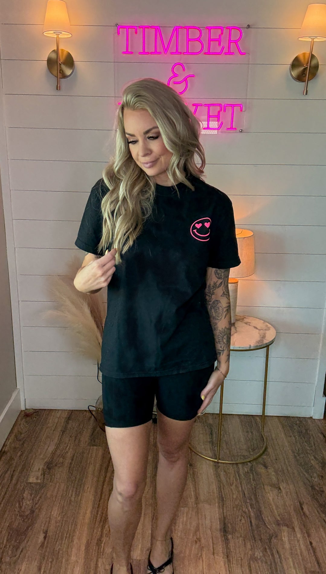 Woman wearing charcoal tee shirt with 'In my cool mom era' in hot pink puff letter graphics and a small hot pink smiley face on the front 