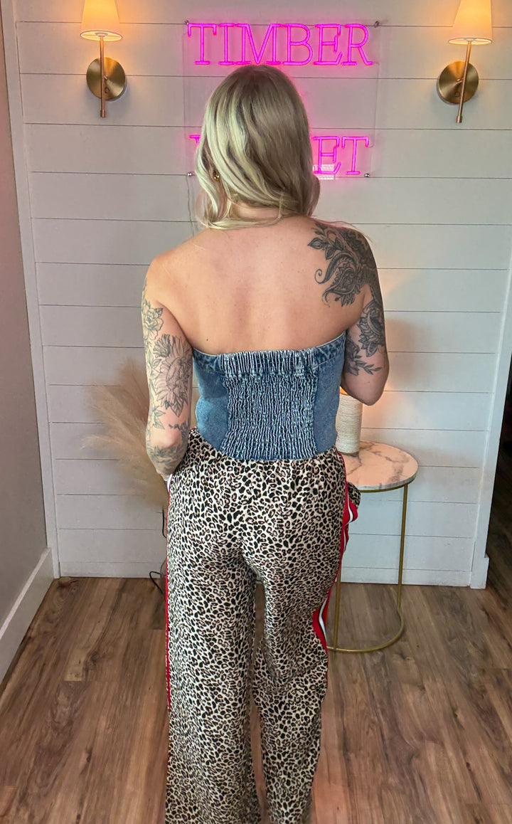 woman wearing denim sleeveless button up corset with two front pockets and with leopard pants and heels 