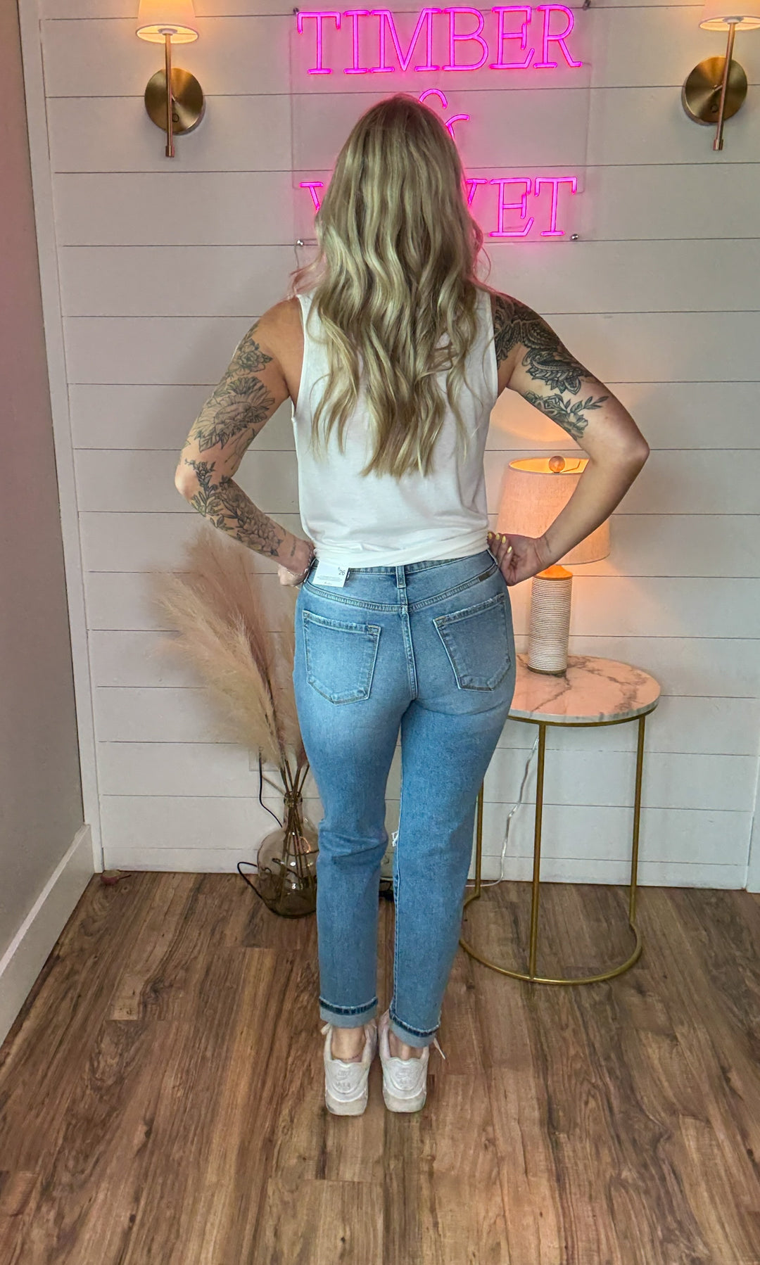 woman wearing KanCan relaxed skinny jean, medium stone wash, and just the right touch of distressing at the knee, button fly with frayed open hem and a white relaxed fit tank top