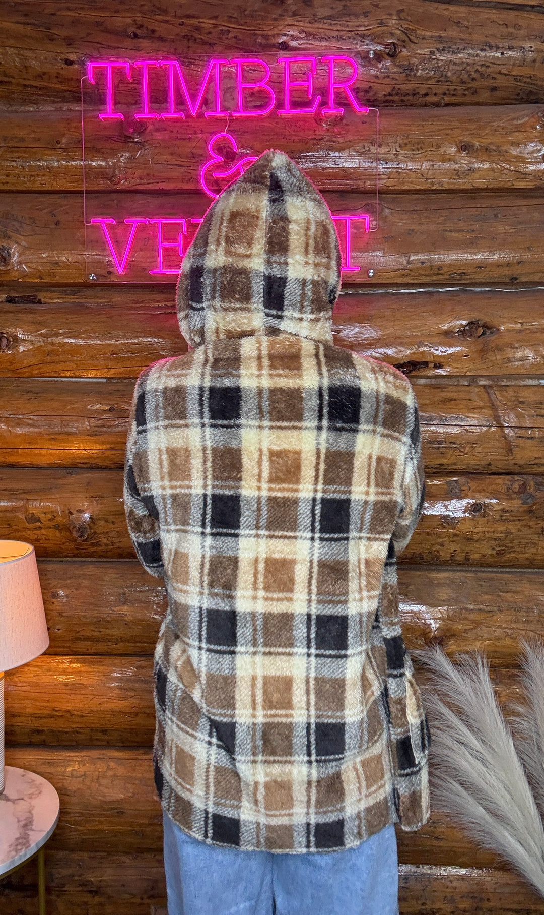 Person wearing a plaid hoodie with 'Timber & Vine' neon sign in the background