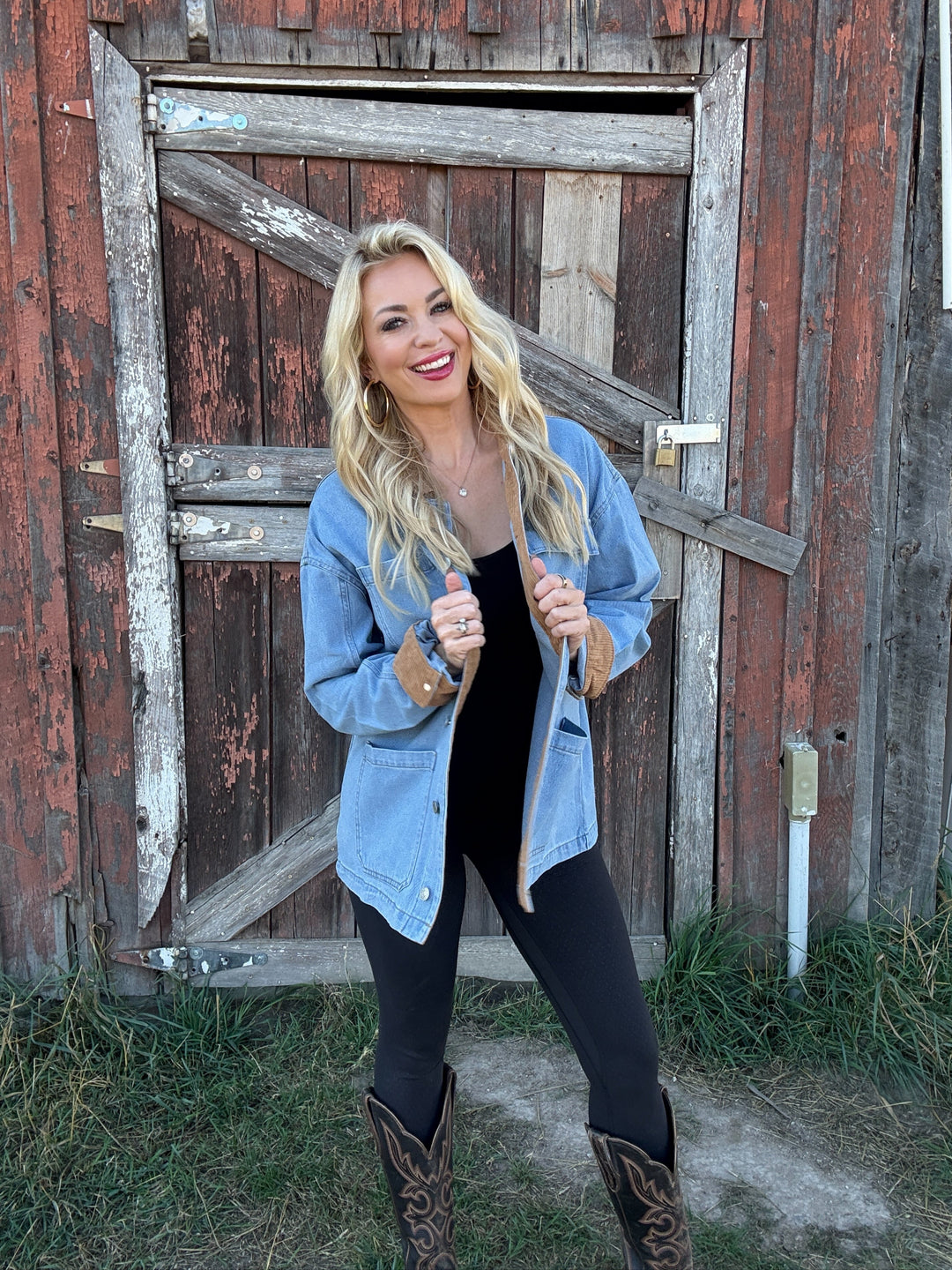 Woman wearing a jean barn jacket standing in front of a rustic wooden door