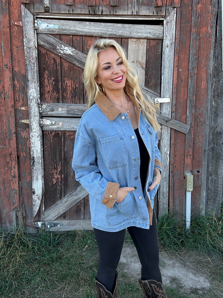 Woman wearing a denim barn jacket in front of a rustic wooden building