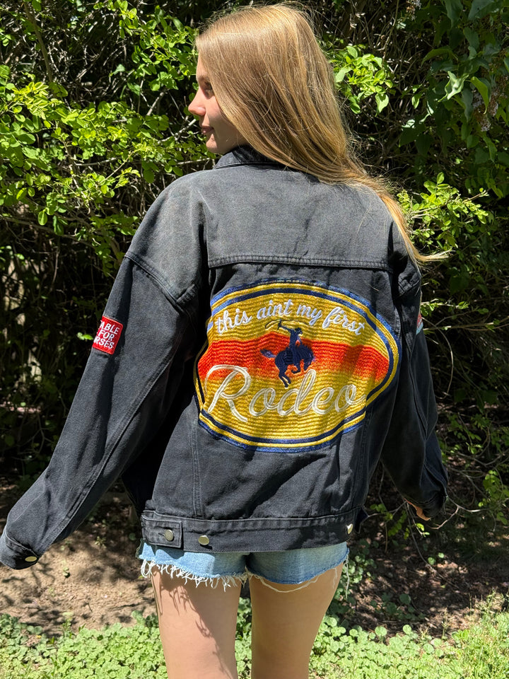 Person wearing a denim jacket with a colorful &