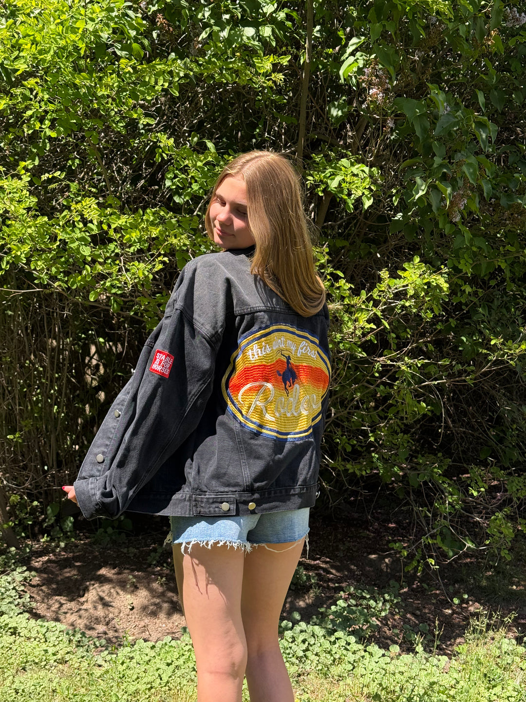 Person wearing a denim jacket with a logo &