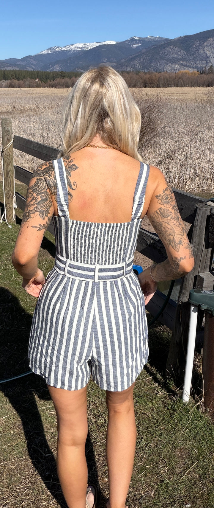 Person wearing a striped romper with mountains in the background