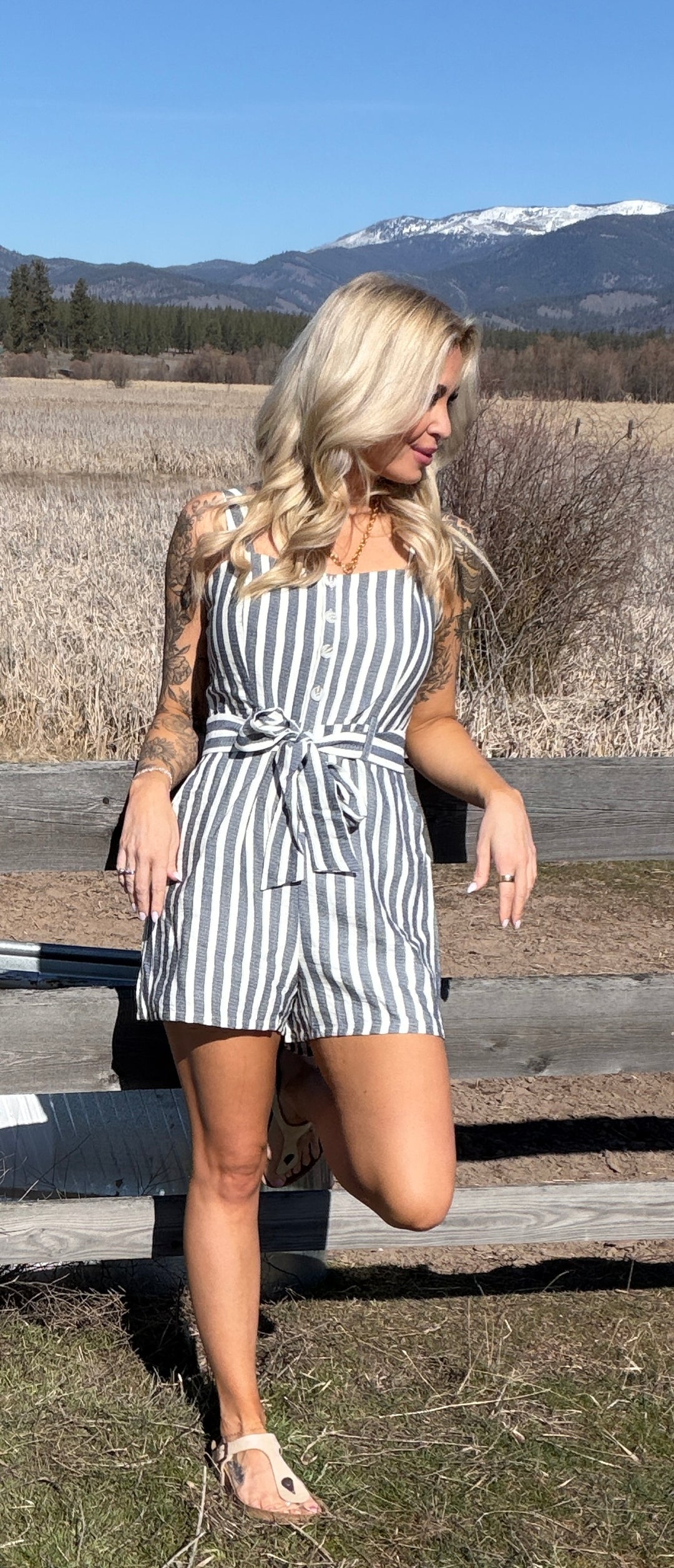 Woman in a striped romper standing outdoors with mountains in the background