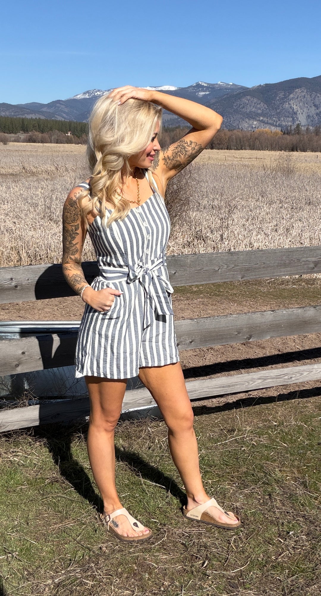 Woman in a striped romper standing outdoors with mountains in the background