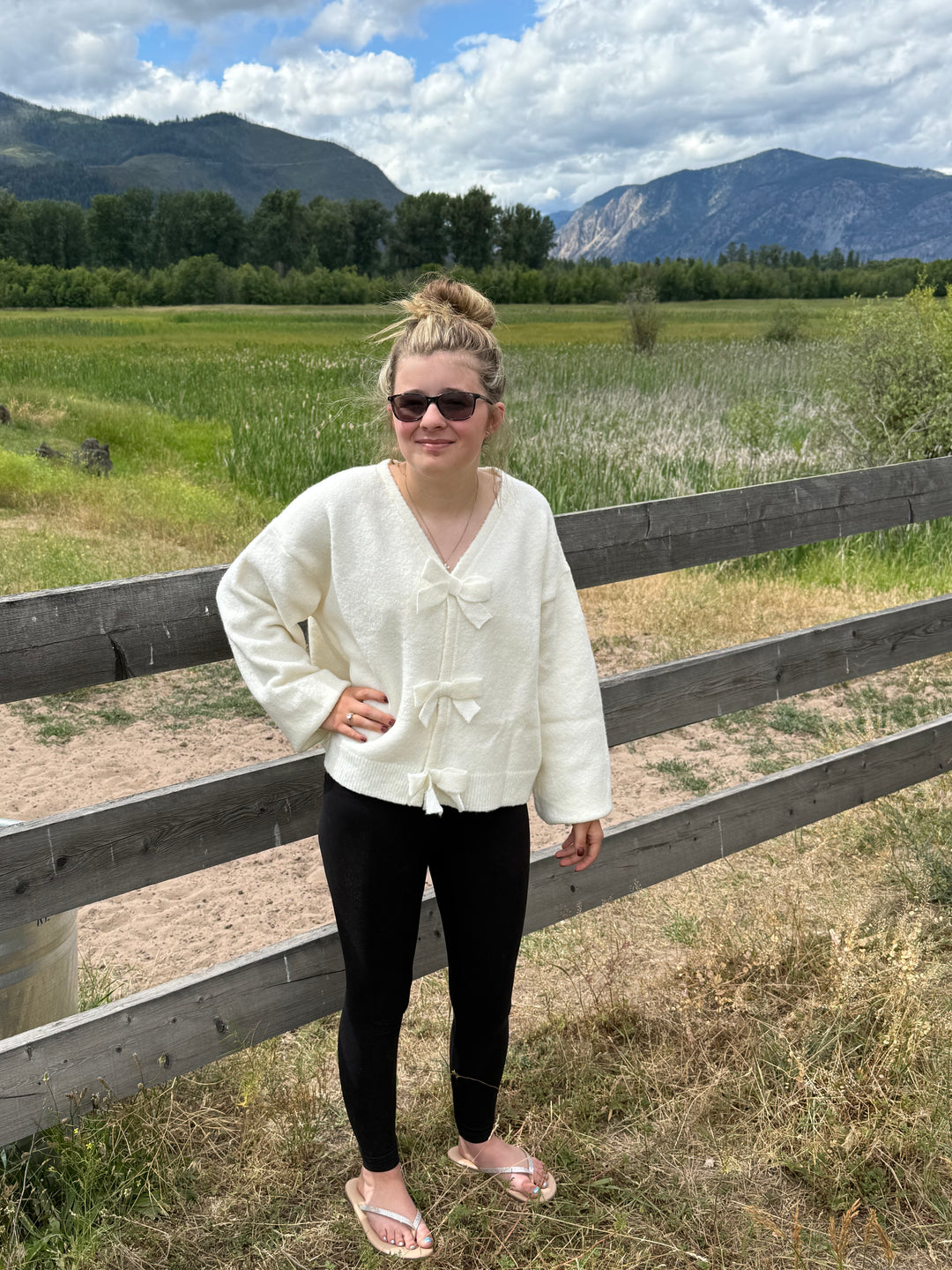 person wearing a dressy cream colored bow cardigan