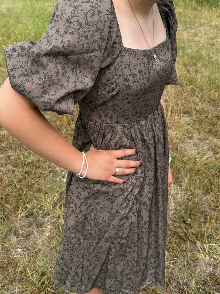 person wearing a Floral dress with puff sleeves and square neckline in chocolate 