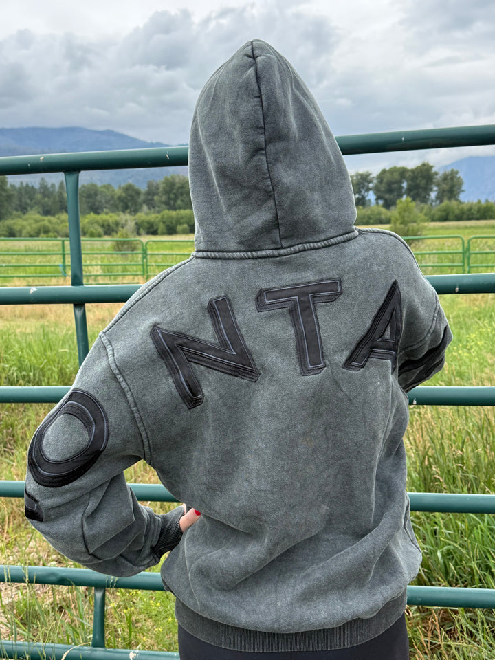 Person wearing a gray hoodie with MONTANA on the back, standing outdoors.