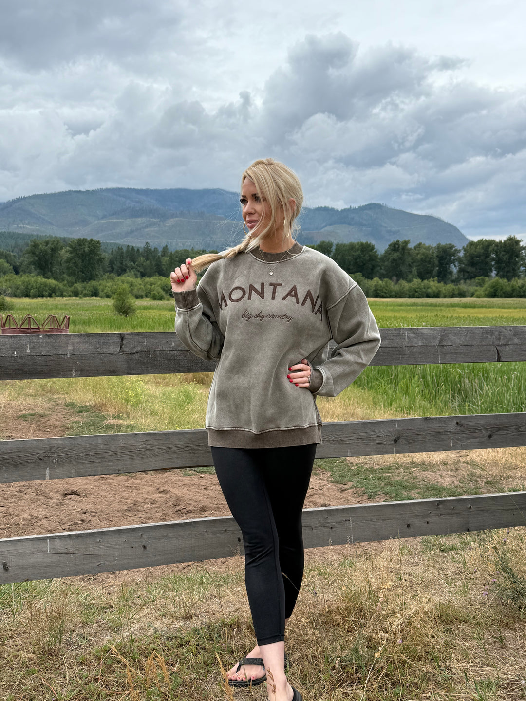 Person wearing a sweatshirt with Montana Big Sky Country Crewneck sweatshirt in acid wash brown