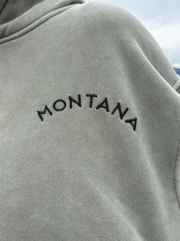 olive sweatshirt with 'Montana' embroidery on a blurred background