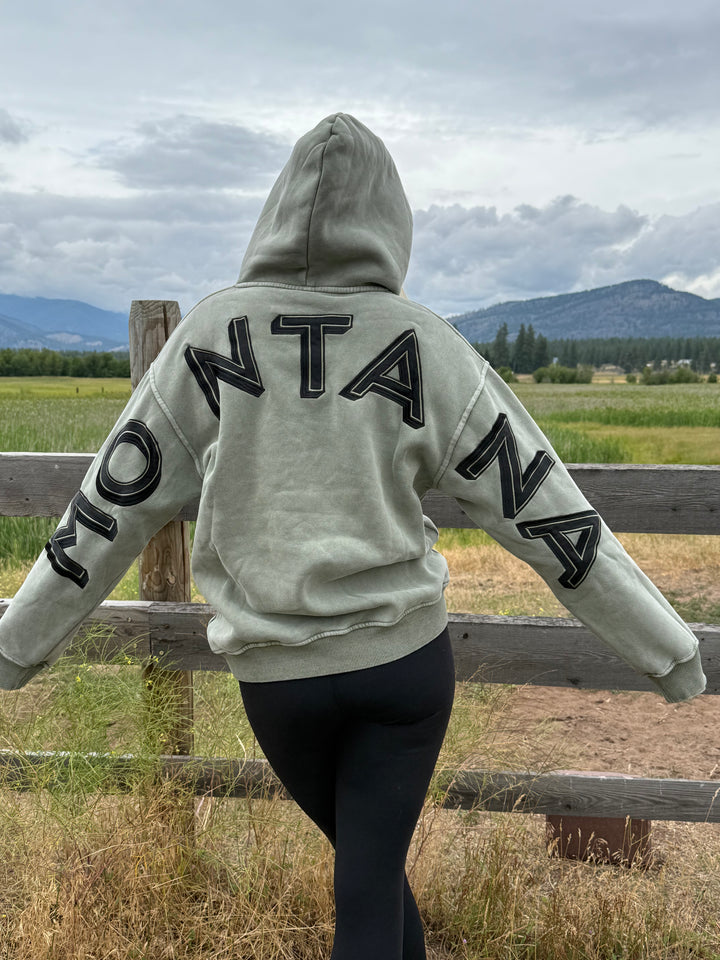 Person wearing a hoodie with 'Montana' text on back of sweatshirt 