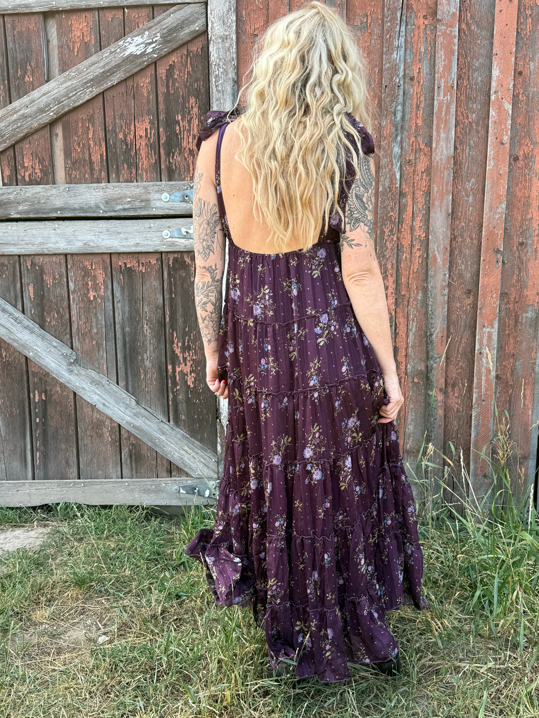 Person wearing a long, dark purple dress with floral patterns 