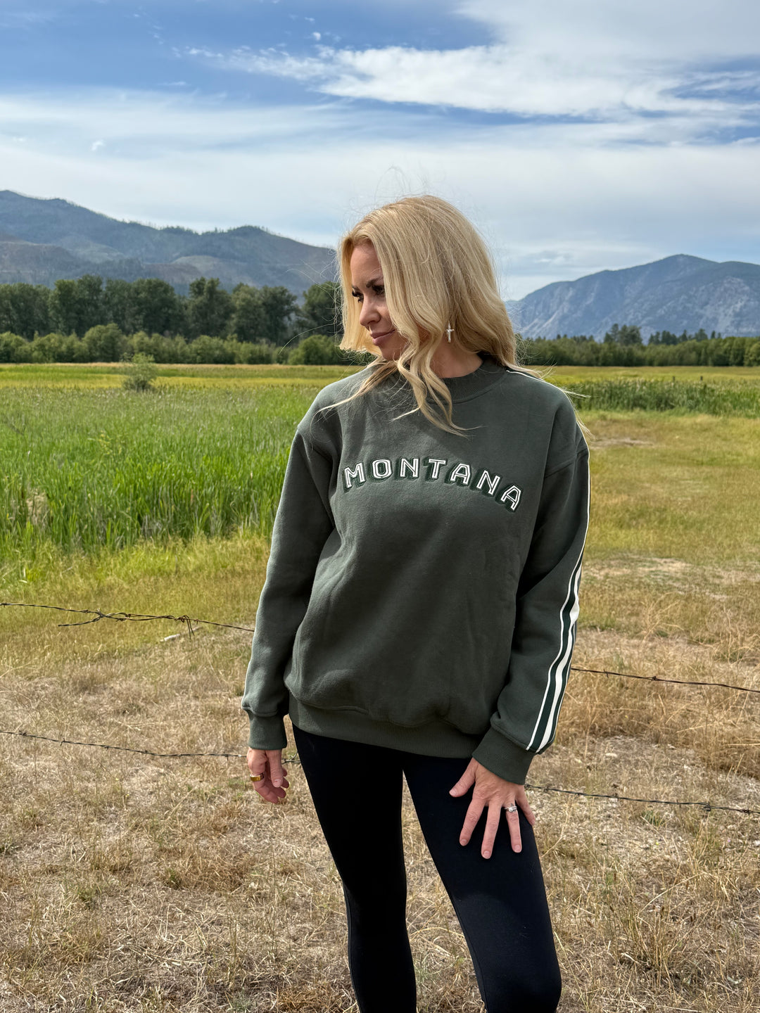 Person wearing a sweatshirt with 'Montana' text in a scenic outdoor setting