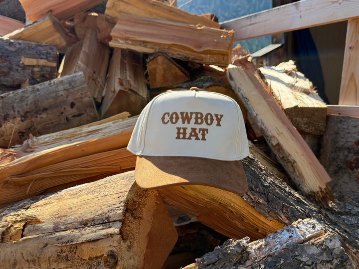trucker hat labeled 'Cowboy Hat' on a pile of firewood