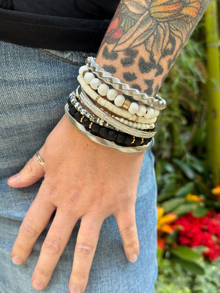 The Wildwood Bracelet Stack -five-piece set features a mix of beads in neutral hues of black, white, and gold