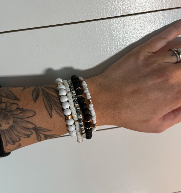 The Wildwood Bracelet Stack -five-piece set features a mix of beads in neutral hues of black, white, and gold