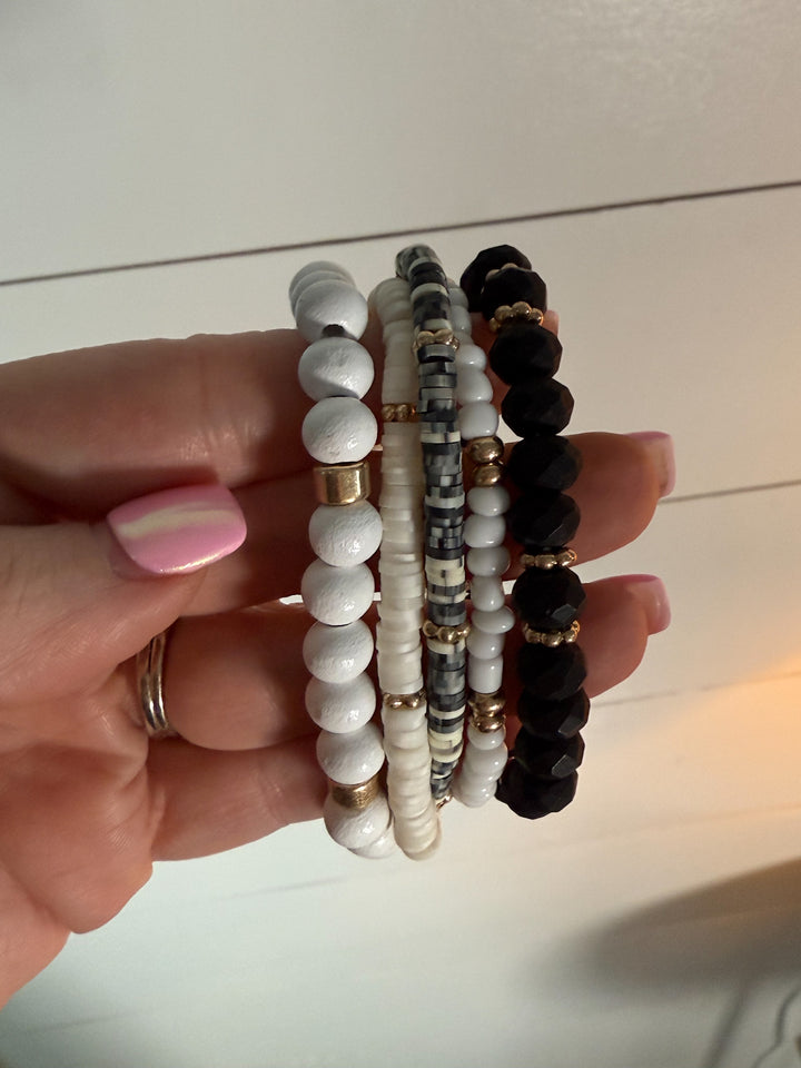 The Wildwood Bracelet Stack -five-piece set features a mix of beads in neutral hues of black, white, and gold