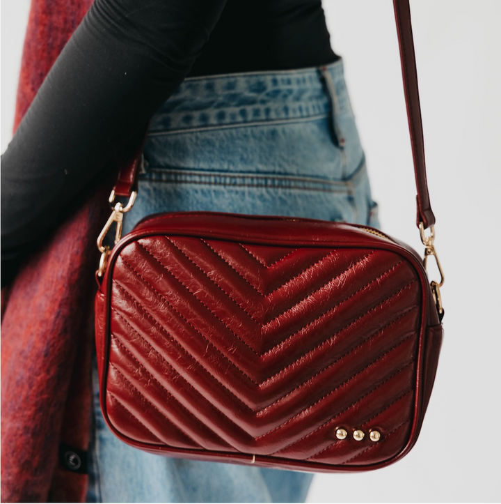 Red chevron-patterned handbag worn over shoulder with a blurred background