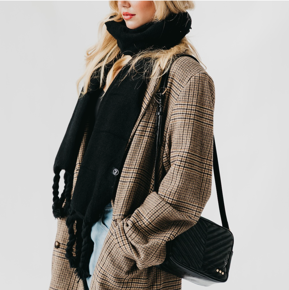 Person wearing a plaid coat, black scarf, and holding a black handbag on a white background