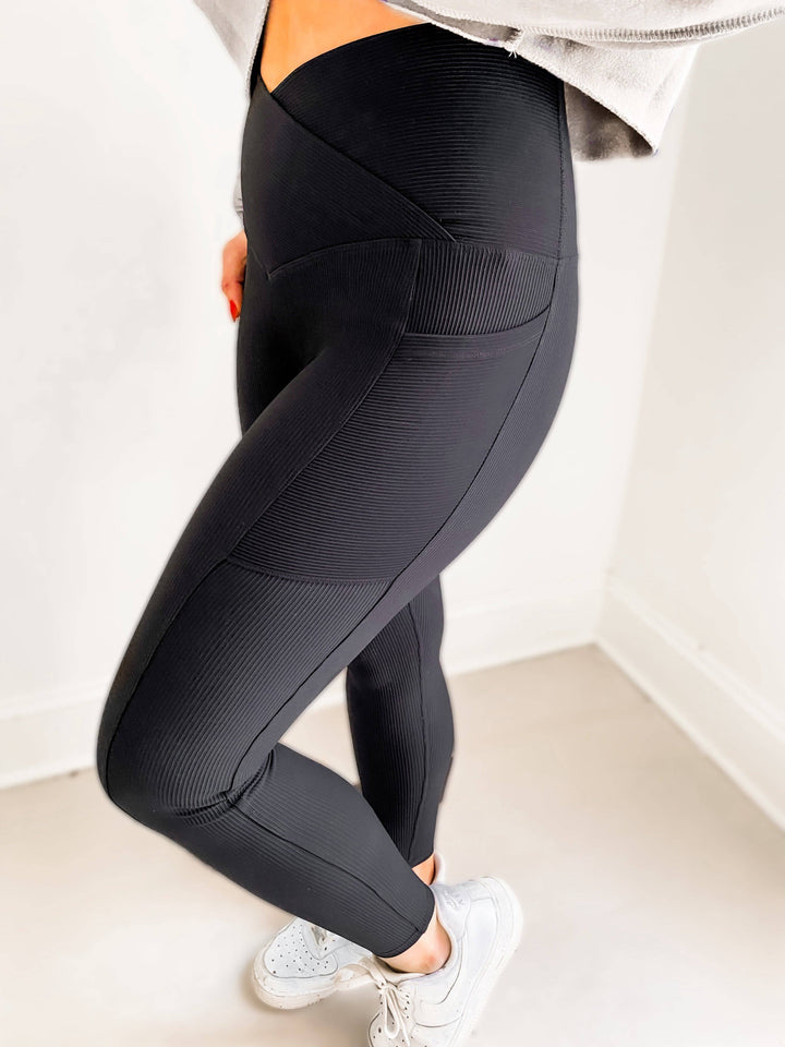 Woman wearing ribbed high compression black leggings with v crossover cut in the front